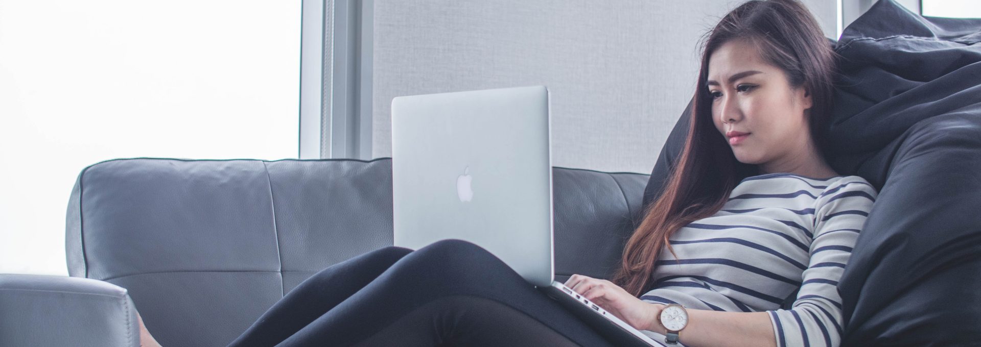 woman sitting on sofa while using MacBook Pro